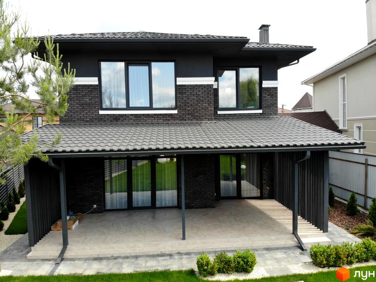 Двоповерховий будинок темно-сірого кольору з цегляним оздобленням та терасою. Котеджне містечко Kulbaba Petropavlivka з доглянутим газоном.