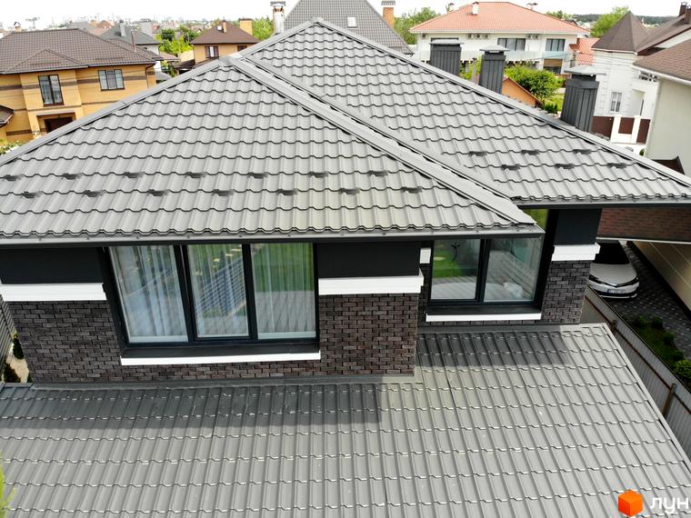 Будинок Котеджного містечка Kulbaba Petropavlivka з темно-сірою черепичною покрівлею та цегляними стінами, видно подвір'я.