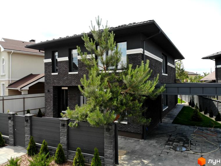 Фасад будинку Котеджного містечка Kulbaba Petropavlivka з темної цегли, великими вікнами та доглянутою прибудинковою територією.