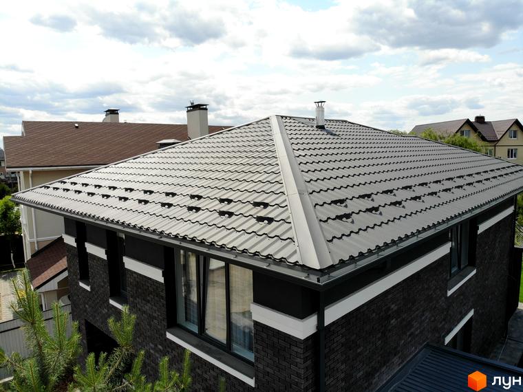 Будинок в Котеджному містечку Kulbaba Petropavlivka з темно-сірою цегляною кладкою, світлими смугами та сірою металочерепицею на даху.