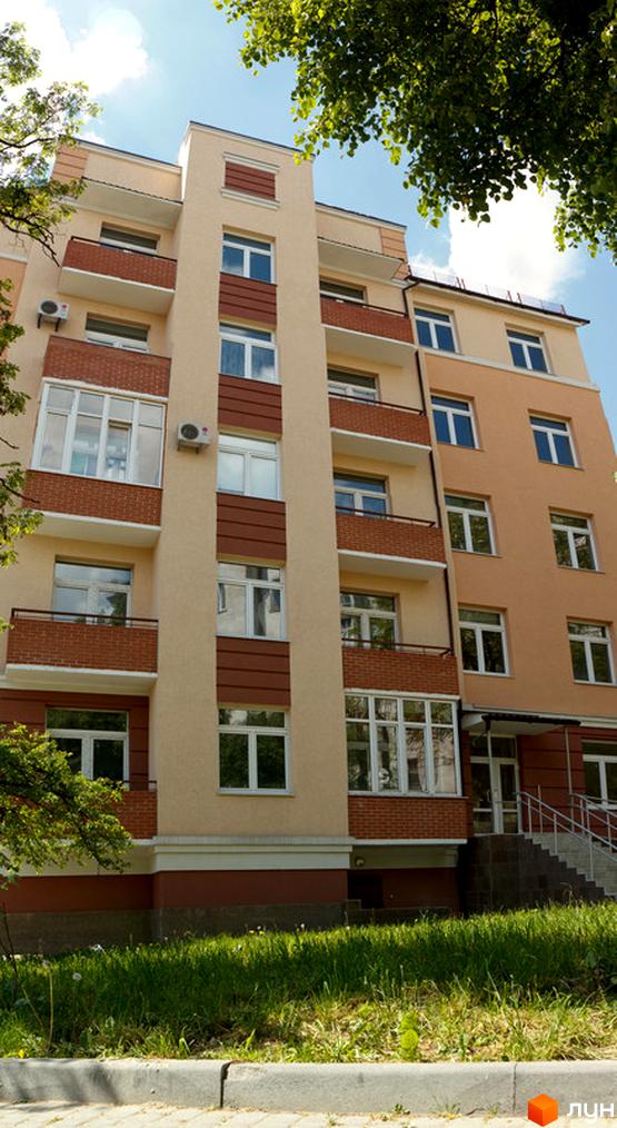 Житловий комплекс на вул. Шкільна, 69, з фасадом з світлих матеріалів та великими вікнами. Приблизна територія з зеленими насадженнями та тротуаром.