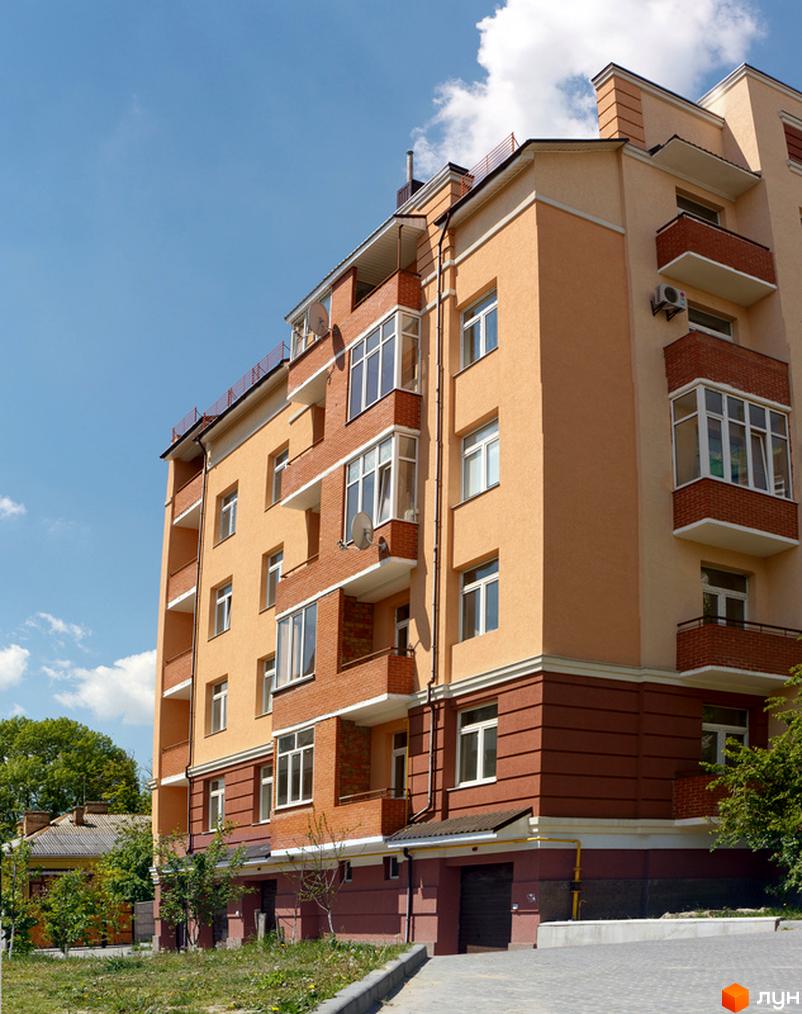 Житловий комплекс на вул. Шкільна, 69, з фасадом в світлих тонах та балконами. Прибудинкова територія з зеленими насадженнями та парковкою.