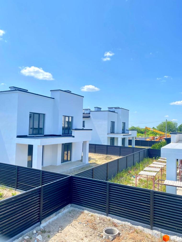 Котеджний комплекс PRIDE Residents: білі будинки з плоскими дахами та темними вікнами. Територія огороджена чорними парканами.