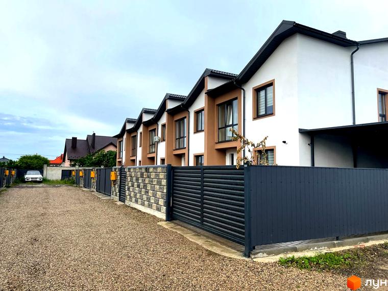 Зовнішній вигляд таунхаусів у WEST TOWN V з коричнево-білим фасадом та сірим парканом. Подвір'я з гравійною дорогою.