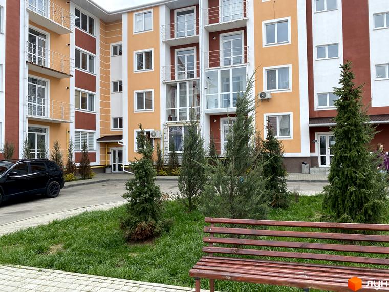Житловий комплекс Амстердам - багатоповерховий будинок з помаранчевим фасадом, балконами та зеленими насадженнями на прибудинковій території.