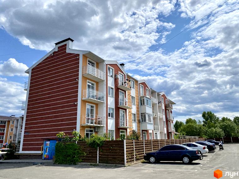 Житловий комплекс Амстердам з балконами та паркуванням на фоні хмарного неба. Сучасна архітектура та доглянута прибудинкова територія.