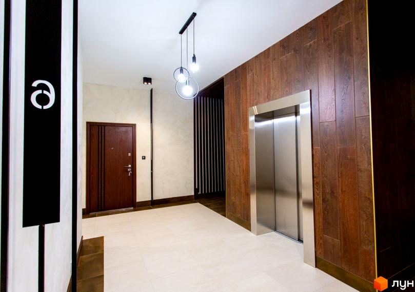 Сучасний хол з дверима та ліфтом у клубному будинку Rezydencja „Zalizna Voda“. Дизайн інтер'єру з дерев'яними панелями та контрастними смугами.