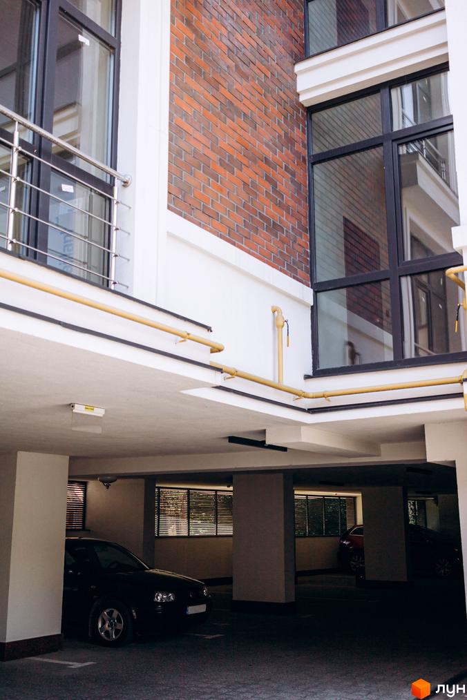 Клубний будинок Rezydencja „Zalizna Voda” з цегляним фасадом та великими вікнами, паркінг з автомобілями.