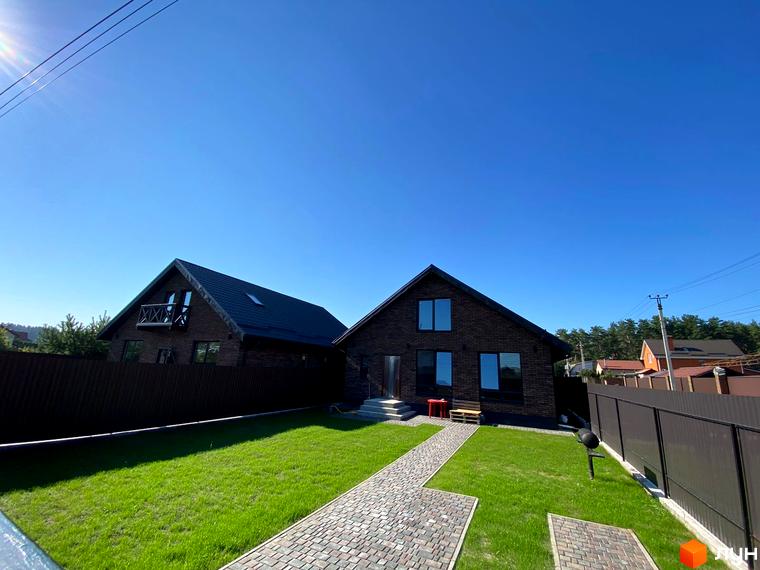 Котеджне містечко КМ Одноповерховий Київ - Білогородка: цегляний будинок з великими вікнами та доглянутою зеленою ділянкою з бруківкою.