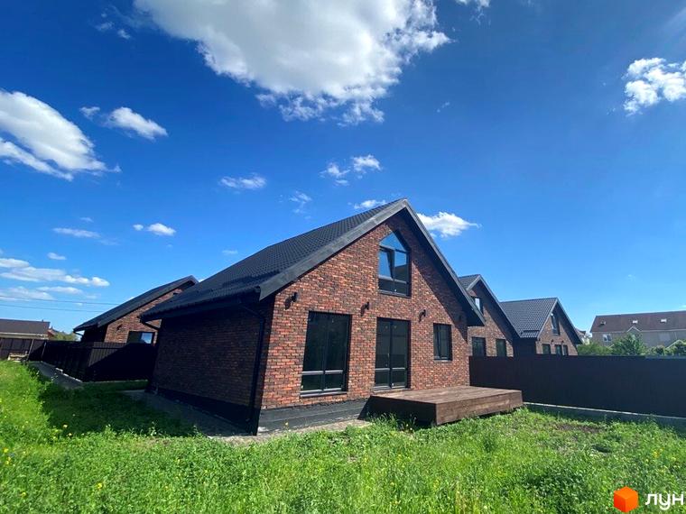 Котеджне містечко КМ Одноповерховий Київ - Білогородка. Цегляні будинки з чорними дахами та вікнами, зелена галявина перед будинками.