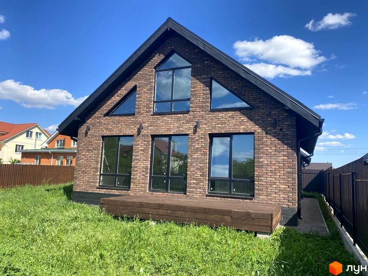 Котеджне містечко КМ Одноповерховий Київ - Білогородка. Фасад будинку з цегли, великі вікна, дерев'яна тераса та зелена ділянка.