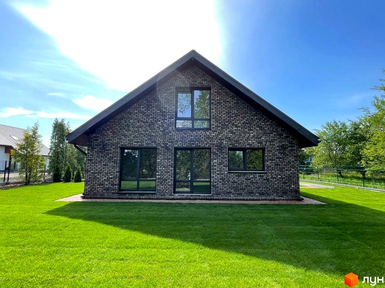 Котеджне містечко КМ Одноповерховий Київ - Білогородка. Будинок з сірої цегли з великими вікнами та доглянутою зеленою галявиною.