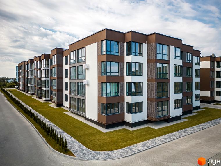 Новобудова ЖК Royal Hill з коричнево-білим фасадом та великими вікнами, оточена доглянутим газоном та вимощеною доріжкою.