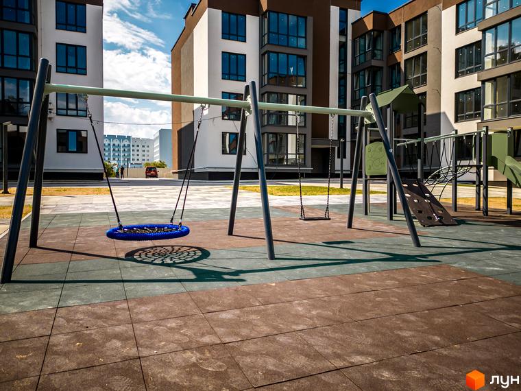 Житловий комплекс Royal Hill: фасади будівель та дитячий майданчик з гойдалками та гіркою. Новий житловий комплекс для вашого комфорту.