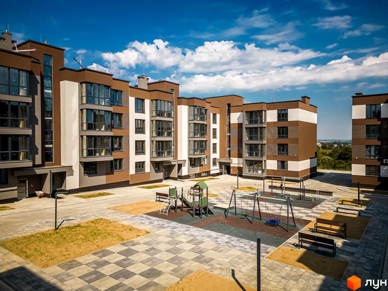 Житловий комплекс Royal Hill: фасади будівель коричневого та білого кольорів, великі вікна. На прибудинковій території дитячий майданчик та місця для відпочинку.