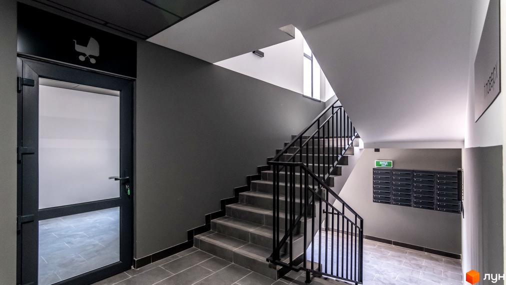 Сходи та двері з символом дитячого візка в житловому комплексі Royal Hill. Вхідна група новобудови з поштовими скриньками та знаком виходу.