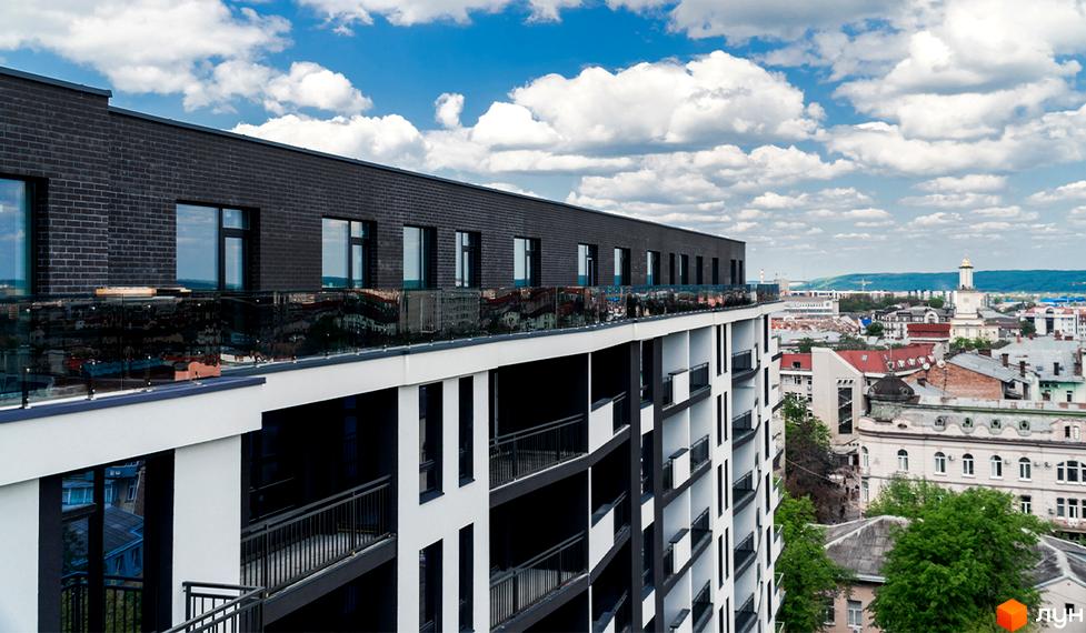 Зовнішній вигляд новобудови ЖК Авторський з балконами та скляними огорожами. Вид на міський пейзаж з висоти пташиного польоту.