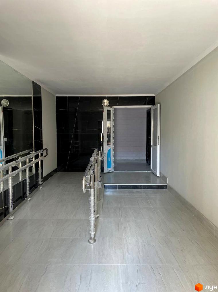 Вхідна група новобудови ЖК на Масанах з пандусом та поручнями. Сучасний дизайн інтер'єру з мармуровою плиткою на стінах та підлозі.