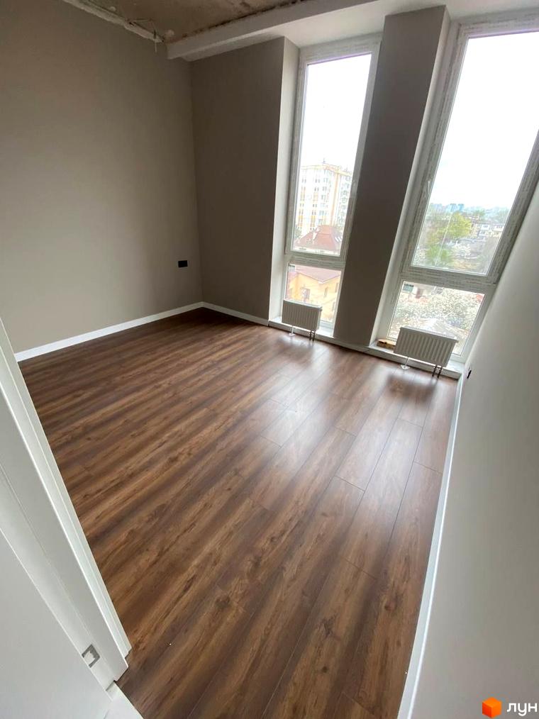 Клубний будинок „Graf на Педагогічній“: простора кімната з дерев'яною підлогою та великими вікнами, що виходять на міський пейзаж.