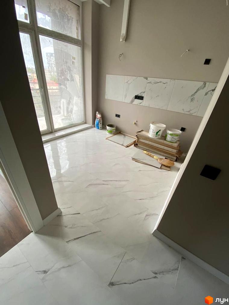 Клубний будинок „Graf на Педагогічній“: фото ремонту квартири з білою плиткою на підлозі та стінах, великим вікном та будівельними матеріалами.