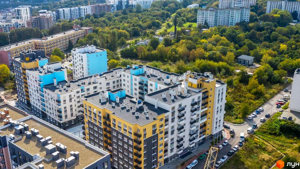 Житловий комплекс Білий Шоколад з яскравими фасадами та упорядкованою прибудинковою територією. На фото видно багатоповерхові будинки з балконами та зелені насадження.