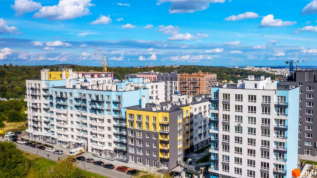 Житловий комплекс Білий Шоколад з яскравими фасадами та балконами, з прибудинковою територією та автомобілями на парковці.