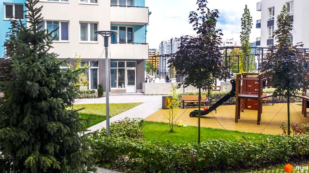 Житловий комплекс Білий Шоколад: фасади будинків та дитячий майданчик з гіркою та лавками.