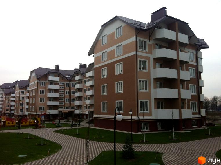 Житловий комплекс Квартал Буча. Багатоквартирні будинки коричнево-бежевого кольору з білими балконами. Прибудинкова територія з доріжками та зеленими зонами.