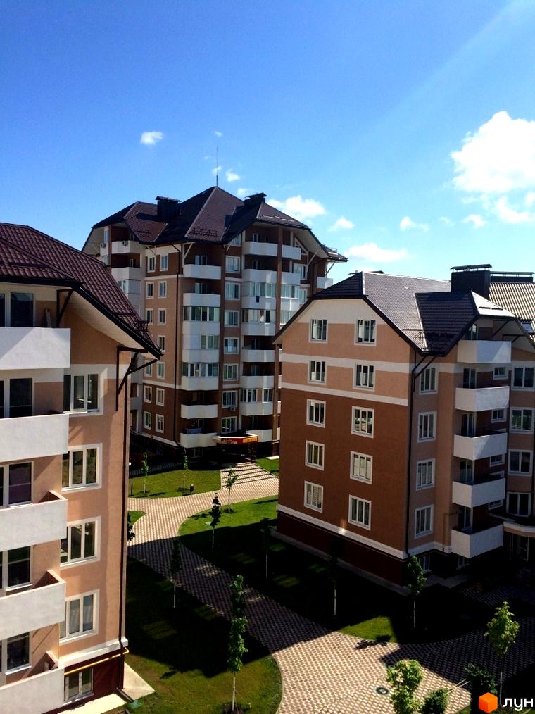 Житловий комплекс Квартал Буча. Багатоквартирні будинки з коричневими дахами та світлими фасадами, облаштована прибудинкова територія із зеленими насадженнями та пішохідними доріжками.