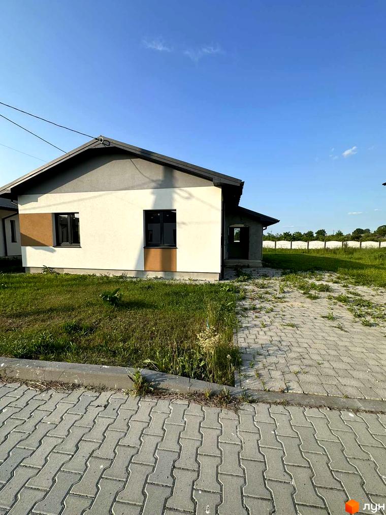 Зображення будинку в Котеджному містечку Горіхова Долина. Вигляд фасаду та прибудинкової території з тротуарною плиткою.