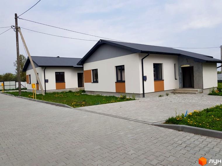 Зображення Котеджного містечка Горіхова Долина: одноповерхові будинки з темним дахом та світлим фасадом, подвір'я викладене бруківкою.