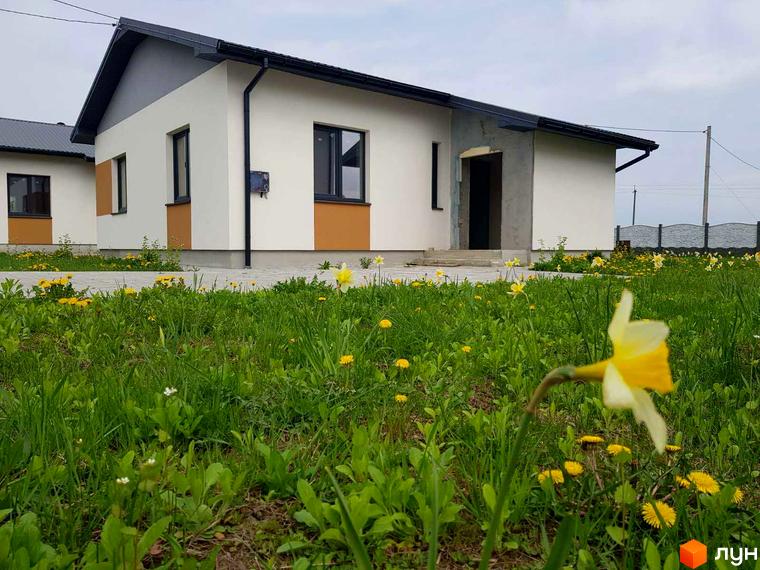 Зображення будинку в Котеджному містечку Горіхова Долина. Вигляд фасаду та прибудинкової території з зеленим газоном.