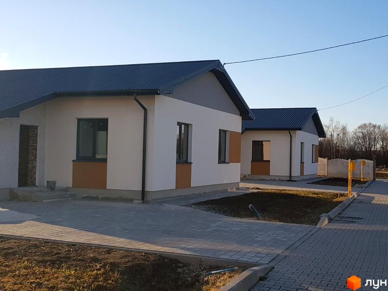 Зображення Котеджного містечка Горіхова Долина. Одноповерхові будинки з темними дахами та світлими стінами, облаштована прибудинкова територія.