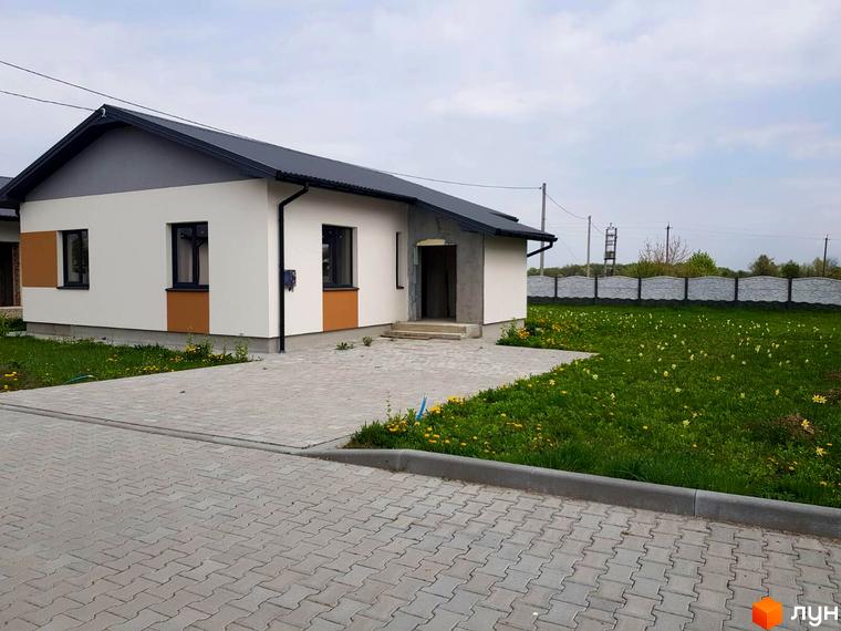 Зображення будинку в Котеджному містечку Горіхова Долина. Вигляд фасаду та прибудинкової території з газоном і тротуарною плиткою.