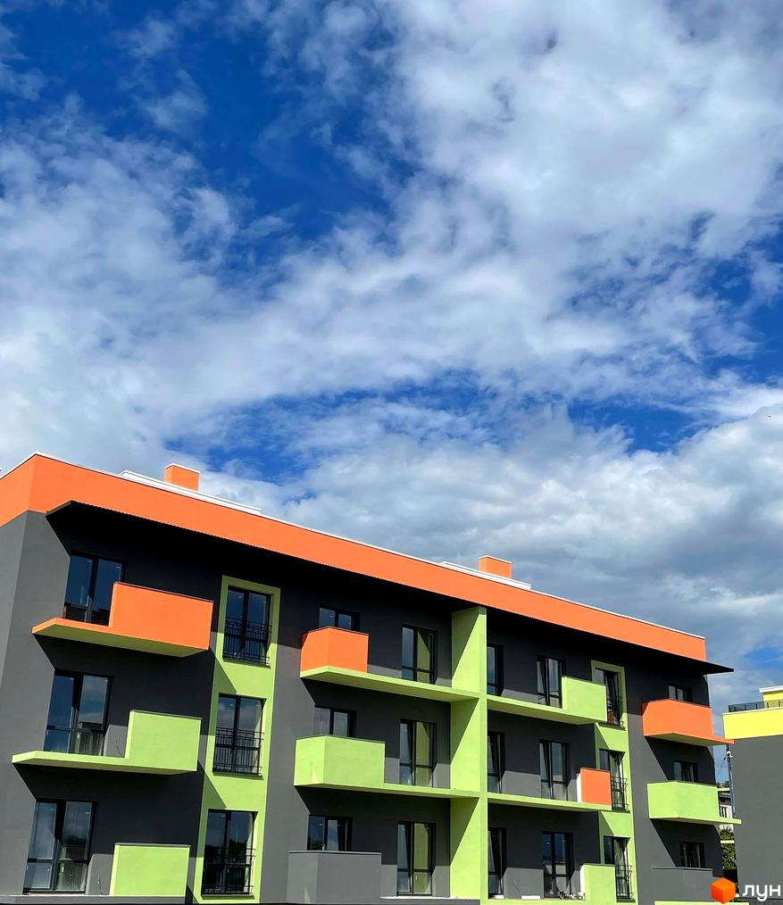 Зображення фасаду Житлового району Долина Троянд з яскравими балконами на фоні блакитного неба. Архітектура новобудови привертає увагу.