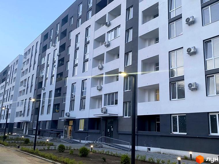 Житловий комплекс Щасливий - багатоповерховий будинок з балконами та кондиціонерами. Прибудинкова територія з освітленням та зеленими насадженнями.