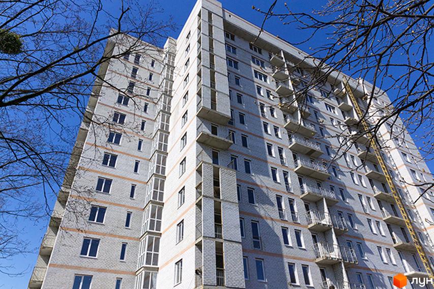 Житловий комплекс на проспекті Петра Григоренка, 18а. Будинок з балконами та прибудинковою територією, оточений деревами.