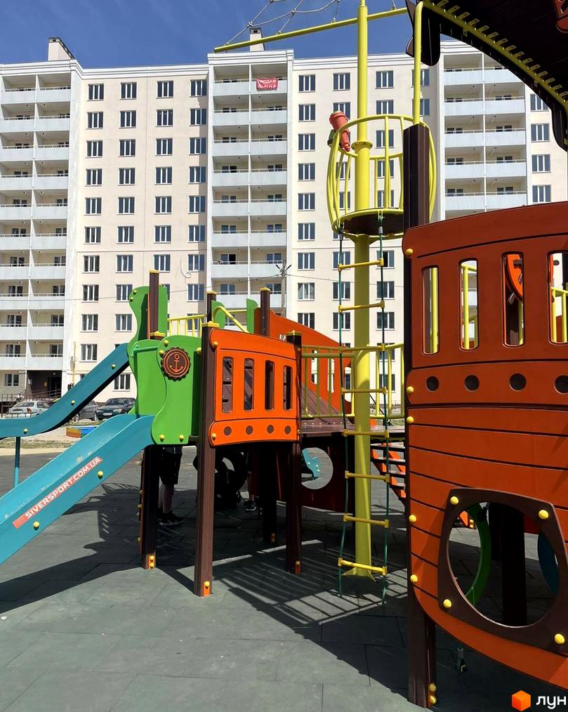 Новобудова ЖК на Масанах. Дитячий майданчик з гірками та елементами корабля на тлі багатоповерхового будинку.