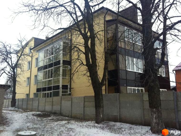 Зовнішній вигляд будинку на вул. Підлісна, 15 з великими вікнами та прибудинковою територією з деревами.