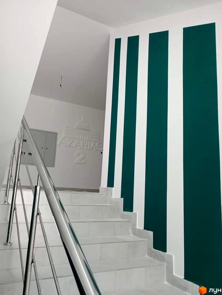 Фото сходового майданчика в Житловому комплексі Azarias 2. Сходи з металевими поручнями, стіни пофарбовані в білі та зелені смуги.