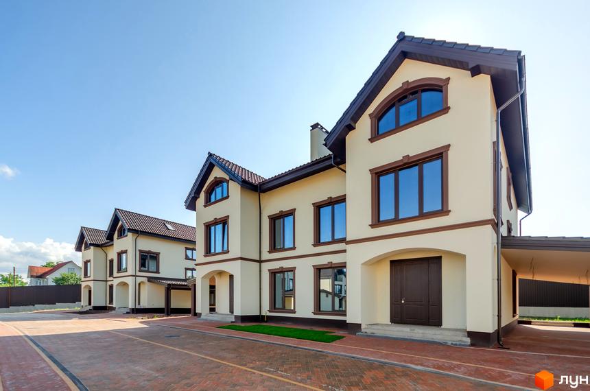 Котеджне містечко КМ Vita Energy residence - це двоповерхові будинки світло-бежевого кольору з коричневими вікнами та дахом, розташовані на брукованій території.