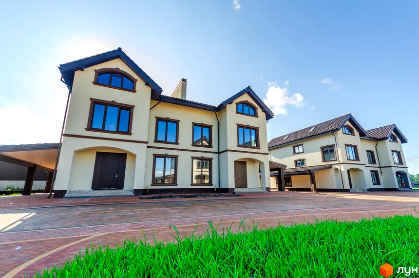 Котеджне містечко КМ Vita Energy residence - двоповерхові будинки світло-бежевого кольору з коричневими вікнами та дахом. Навколо будівель розташована бруківка та зелена галявина.