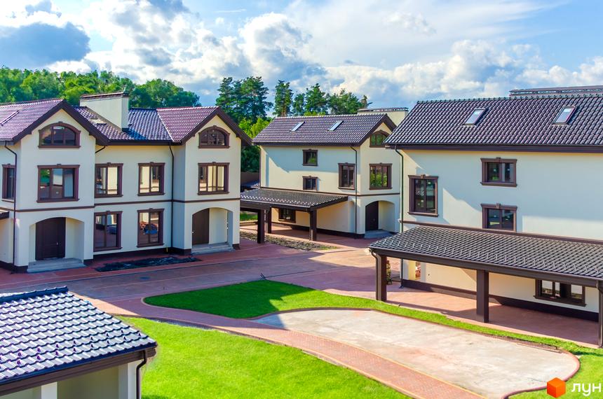 Котеджне містечко КМ Vita Energy residence. Зовнішній вигляд двоповерхових будинків з коричневими дахами та прибудинкова територія з зеленими газонами та доріжками.