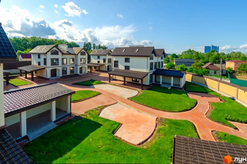 Котеджне містечко Vita Energy residence: білі двоповерхові будинки з коричневими дахами та навісами, зелені газони та доріжки з бруківки.