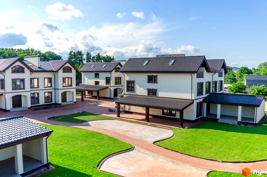 Котеджне містечко КМ Vita Energy residence: двоповерхові будинки з коричневими дахами та великими вікнами, зелена галявина та доріжки з червоної плитки.
