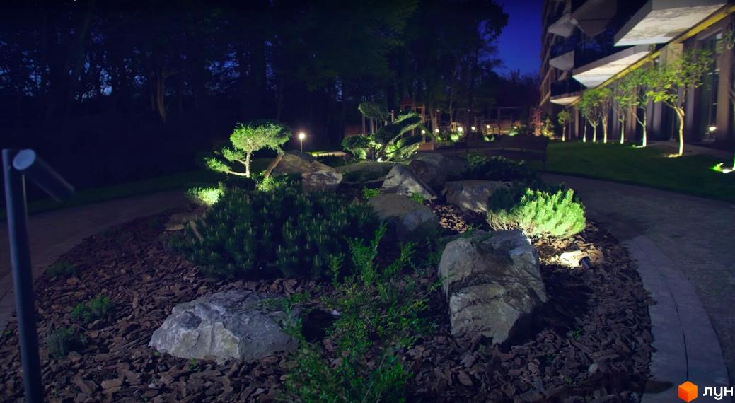 Житловий комплекс Tiffany. Зовнішній вигляд будівлі та освітлена прибудинкова територія з рослинами та каменями.