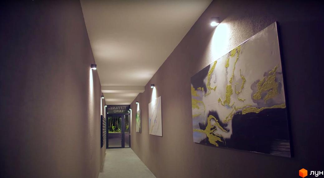 Комплекс Tiffany. Коридор з картинами та освітленням, що веде до входу.