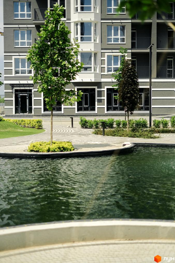 Зовнішній вигляд будинку в Житловому комплексі Гранд Бурже. На передньому плані - водойма та зелені насадження.