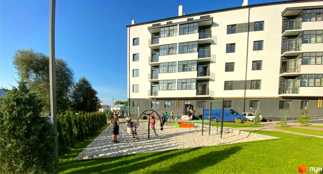 Багатоповерховий будинок Житлового комплексу Місто Комфорту на Лісневицькій. Поруч дитячий майданчик та зелений газон.