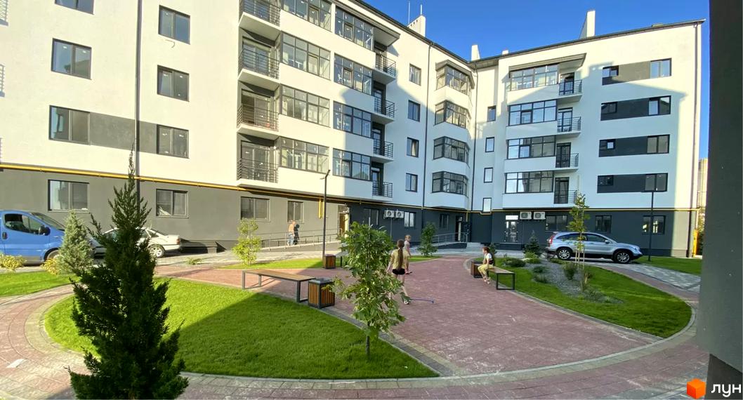 Зовнішній вигляд будинку у Житловому районі Місто Комфорту на Лісневицькій. На території є зелені насадження, лавки та пішохідні доріжки.